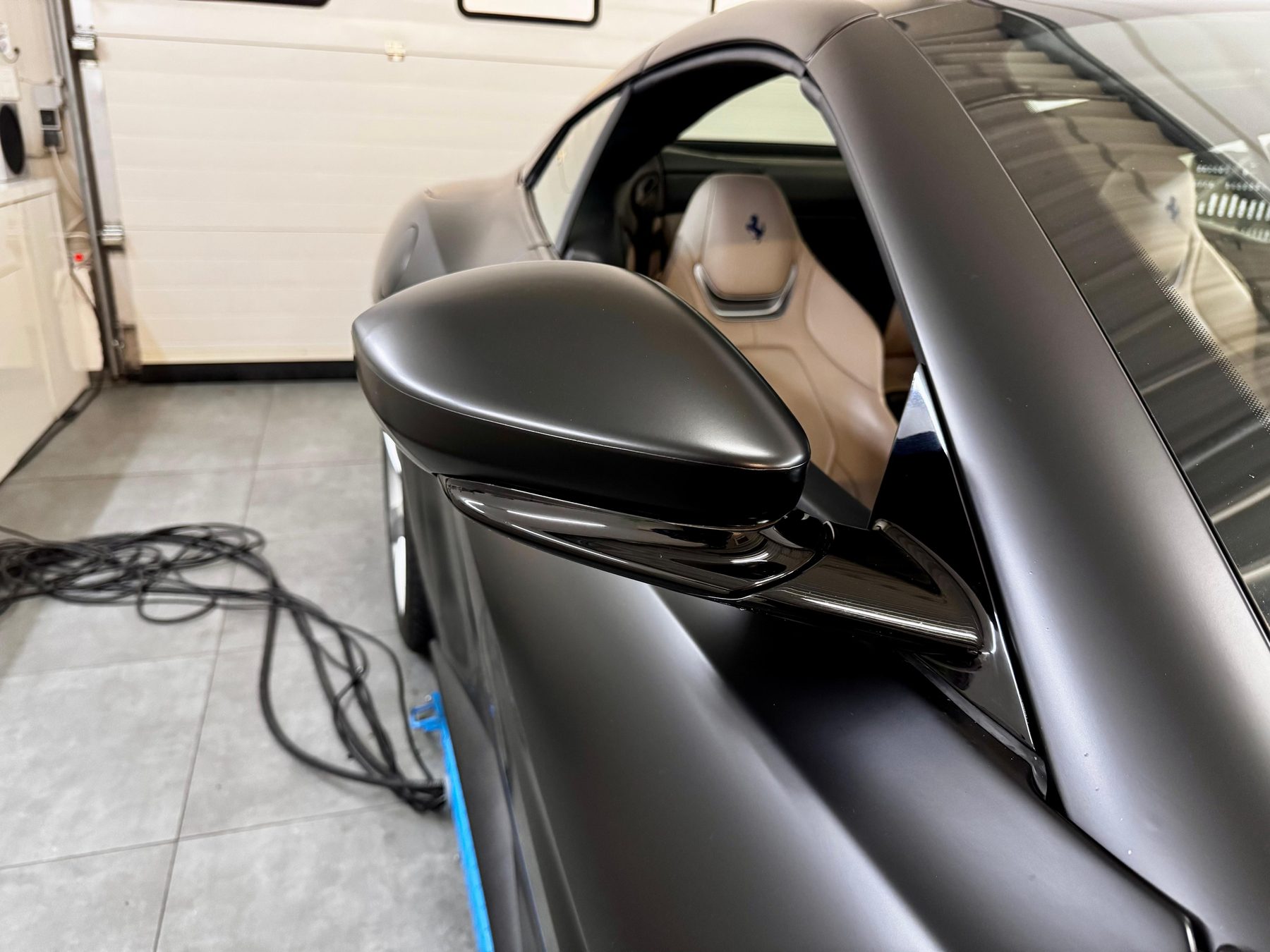 Detailaufnahme eines Außenspiegels nach einer Ferrari-Vollfolierung in Mattschwarz